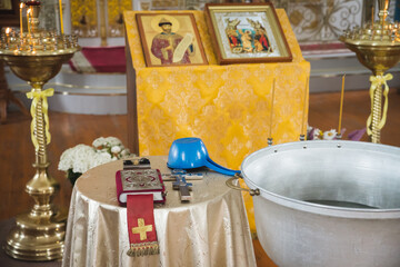 Christening in the church, Big bowl of water for the baptism of a baby with wax candles. Orthodox...