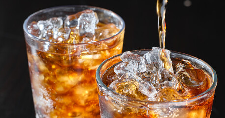 two cups of cola soft drink being poured into glass