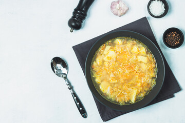Chicken soup on black bowl on dark black stone table.