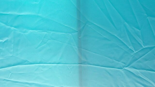Inside view of the wrinkled fabric of a tent's roof flapping in the wind with the sound of the sea waves in the background