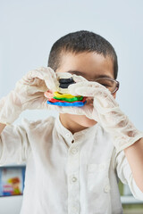 A portrait of cute boy in protective gloves and glasses making plasticine figures on the table