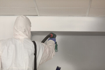 A builder in uniform works with a spray gun. An economical and effective way to paint walls