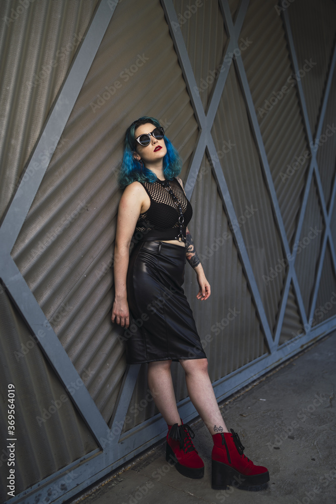 Canvas Prints Cool young lady with blue hair, sunglasses, wearing a crop top, leather pencil skirt and red shoes