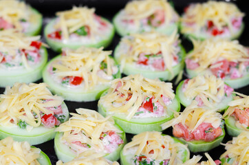 Raw zucchini cooked for baking, stuffed with vegetables and herbs, sprinkled with cheese on top. Selective focus