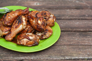 Roasted chicken drumsticks with spices in the orange plate on a wooden table