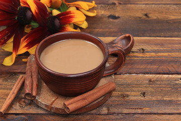 Autumn flower arrangement, cup of coffee with cinnamon and flowers on a wooden table, hyuge style, concept of modern coffee shop