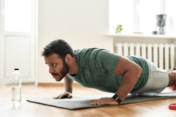 Fight for fit body. Young active man looking focused, exercising, doing push ups during morning...