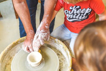 Children making pottery during ceramic lesson with clay