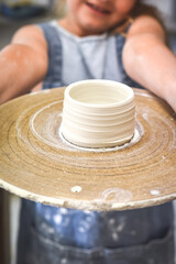 Obraz premium Child holds up a bowl made during ceramic pottery making class