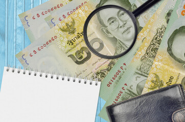 20 Thai Baht bills and magnifying glass with black purse and notepad. Concept of counterfeit money....