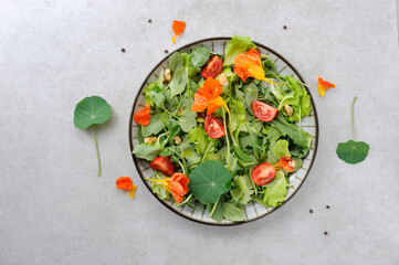 Salad with edible flowers nasturtium  on the gray background.