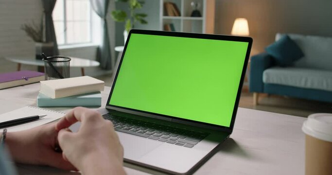 Remote worker having an online video conference with employees or customers, gesturing while talking, using his chroma key green screen laptop computer for connection close up 4k template
