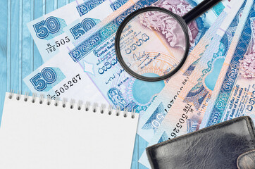 50 Sri Lankan rupees bills and magnifying glass with black purse and notepad. Concept of...