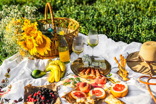Picnic with wine and cheeses in a green park. Romantic dinner in the park