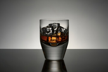 Whiskey auf Eiswürfeln im Glas auf dunkler reflektierender Oberfläche mit grauem Hintergrund
