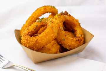 A view of a basket of onion rings, in a restaurant or kitchen setting.