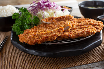 A view of a plate of chicken katsu, in a restaurant or kitchen setting.