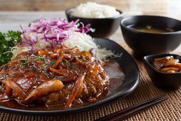 A view of a plate of hamburg steak, in a restaurant or kitchen setting.
