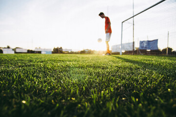 Soccer player on a football field training at sunset