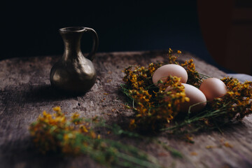 Fresh eggs in the nest of Saint John's wort on a wood table