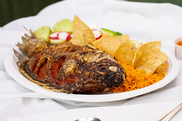 A view of a plate of mojarra frita, in a restaurant or kitchen setting.