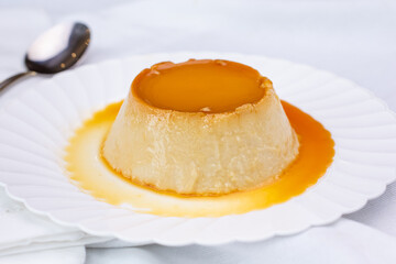 A view of a plate of flan, in a restaurant or kitchen setting.