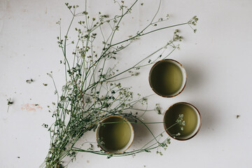 Top view - Cups of green tea with herb on a white table