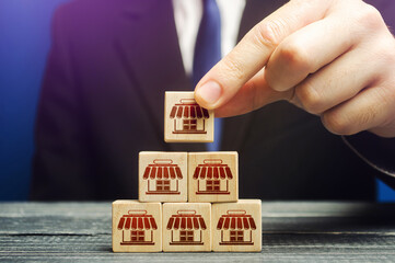 A man builds a pyramid from blocks of business shops. Building a successful business empire....