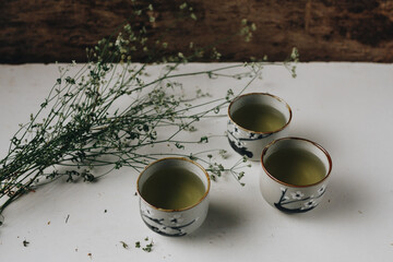 Obraz na płótnie Canvas Three cups of green tea with herbs