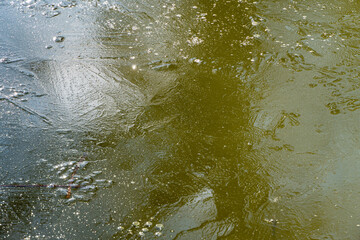 Natural ice structure on surface of frozen pond. Beautiful ice patterns. Close-up. Abstract background from icy surface of pond of dark steel color. Selective focus. Nature concept for winter design.
