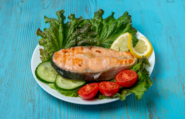 large piece of salmon, lettuce, tomato and lemon