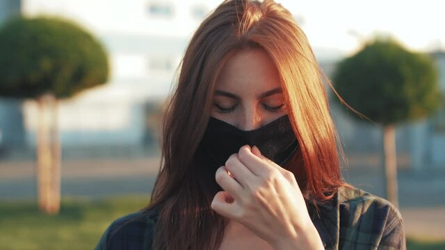 Pandemic Covid-19 coronavirus protection. Portrait of a european hipster woman wearing protective mask on street.Concept of health and safety life. Red-haired woman in black mask