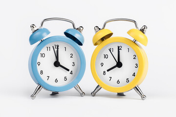 Two round alarm clocks yellow and blue on the white background.