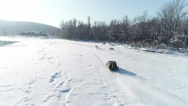 ATVs race on the snow. Aerial view: Rider drivings in the quadrocycle and hovercraft in the cross racing. Extreme sport in winter. Sunny day, mountains scenery on background.