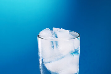 fresh ice water glass close up over blue background. copy space. ice drink at summer season. refreshment beverage. healthy lifestyle concept