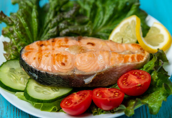 large piece of salmon, lettuce, tomato and lemon