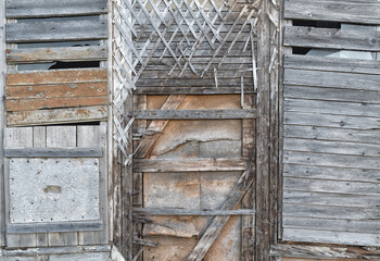 Old wooden walls with plaster crossed base with window covered with boards.