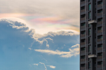 Cloud iridescence (cloud in rainbow colors) with a high-rise building in Bangkok.