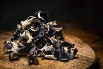 Close up of dry black sliced mushroom on wooden background. Edible dark fungus - auricularia...