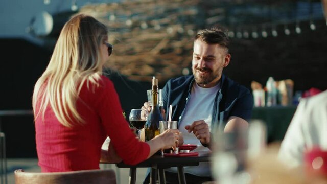 At sunlight young relaxing man and woman drinking cocktail cheers in street cafe time together date food girlfriend meal cheerful portrait slow motion