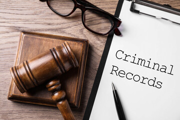 Clipboard with words CRIMINAL RECORD and gavel on wooden table, flat lay