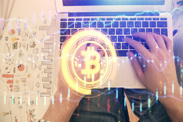 Double exposure of man's hands typing over computer keyboard and crypto currency theme hologram...