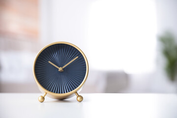 Stylish black clock on white table indoors. Space for text