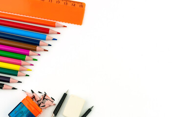 Multi-colored pencils, eraser, ruler, sharpener and compasses on a white background.
