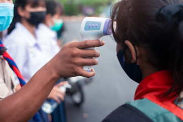 Hand holding Infrared thermometer gun forehead temperature test to check student for protect virus covid-19 symptoms in the school