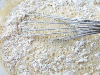 Whipping eggs and flour in bowl.  Cooking the dough.