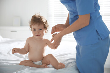 Obraz na płótnie Canvas Orthopedist examining little baby on bed indoors