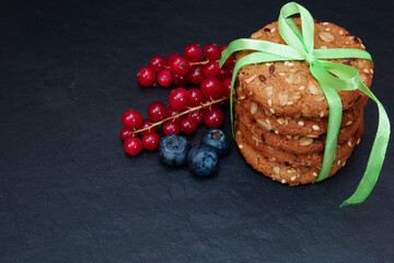 Cookies with berries. Nut biscuits and blueberries with red currants on a black background