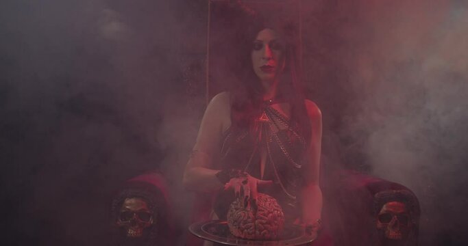 Creepy succubus is sitting on the throne and touching a human brain, smoke, 4k