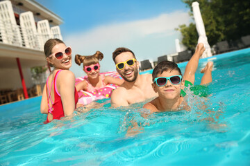 Happy family in swimming pool on sunny day